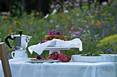 Frühstückstisch in bunter Blumenwiese mit Waffeln und Kaffee