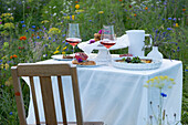 Gedeckter Tisch mit Essen und Roséwein in Blumenwiese