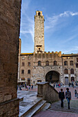 Touristen auf der Piazza del Duomo mit Torre Rognosa in der mittelalterlichen Stadt San Gimignano, Italien.