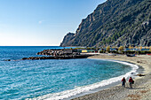 A couple walking on the beach in the off season at Monterosso al Mare, Cinque Terre, Italy.