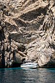 A powerboat pulls away from a small grotto in the limestone cliffs of the island of Capri, Italy.