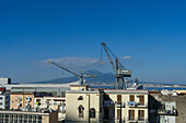 Kräne der Fincantieri-Werft in Castellammare di Stabia auf der sorrentinischen Halbinsel, Italien. Der Vesuv ist im Hintergrund zu sehen.