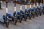 A row of rechargeable electric scooters for rent in front of the train station in La Spezia, Italy.