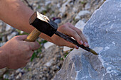 A tourist practices chiseling marble at a marble carving studio in Fantiscritti, Carrara, Italy.