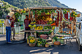 Tourists shop at a roadside vendor's produce stand by the Amalfi Coast road near Positano, Italy.