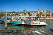 Passenger touristic cruise ship in the Seine river is moored to the pier near Louvre museum