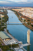 Spectacular panorama shows the Guadalquivir River and Seville's vibrant cityscape from the Mirador de la Torre Sevilla at sunset.