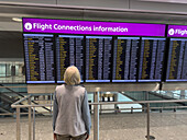 A traveler looks at the flight connections information screen at Heathrow Airport, London, England.