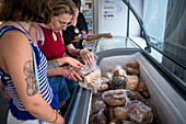 Poor and vulnerable families collecting donated products in the supermarket Rebost Solidari de Gracia, Gracia neighborhood, Barcelona, Spain, Europe. The Rebost Solidari de Gracia is a distributor entity of the Food Bank in its Sec, SERMA (fresh fruit and vegetables), cold chain (frozen and refrigerated products) and FEGA (products received from the EU) programs. An efficient management of all the food surpluses generated by the neighborhood (markets, supermarkets, shops, companies, restaurants, school canteens and others) is an important enough objective in itself, both for its use in the nei