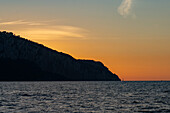 A sailboat at sunset in the Tyrrhenian Sea off the coast of the island of Capri in the Bay of Naples, Italy.