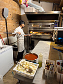 A young man makes pizza in a pizzaria restaurant in Florence, Italy.