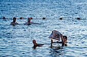 Young woman floating and reading a magazine in the dead sea, Jordan