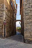 A medieval architecture on a narrow side street in the walled city of San Gimignano, Italy.