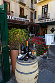 Wine bottles on a wine barrel in front of a restaurant in the historic center of Sorrento, Italy.