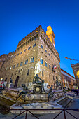 The Fountain of Neptune and the Palazzo Vecchio lit up at twilight in Florence, Italy.