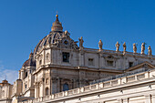 A clock and statues on the facade of Saint Peter's Basilica in Vatican City in Rome, Italy.