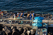 Tourists sunbathing on a recreation pier in the Bay of Naples at Sorrento, Italy.