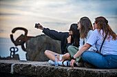 Friends in the the comb of the wind - Peine del viento sculptures of Eduardo Chillida at the foot of the Igeldo mountain in San Sebastián, Gipuzkoa, Basque country, Euskadi, Spain.