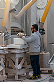 A sculptor makes reference marks on a block of marble in a marble carving studio in Carrara, Italy. He is using a cast resin model for reference.