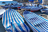 Boats with striped covers on the beach in off peak season at Monterosso al Mare, Cinque Terre, Italy.