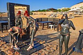 People covered in black Dead Sea mud and salts that have therapeutic healing properties that are highly beneficial at Crowne Plaza Dead sea hotel in the dead sea beach, Jordan.