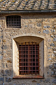 An window with iron bars on a building in the medieval walled town of San Gimignano, Italy.