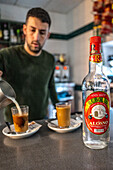 Alosno, Spain, Dec 14 2024, Scene of a bartender serving coffee and liquor with a liquor bottle in Alosno.