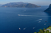 A high-speed passenger ferry heads from Capri to Naples, Italy. The Sorrento Peninsula in the background.