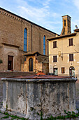 The well or cistern in the Piazza San Agostino with the Church of San Agostino behind. San Gimignano, Italy.