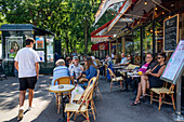 People sitting at La Liberte cafe restaurant on a street avenue in Montparnasse Paris France EU Europe