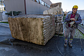 A worker powerwashes a large block of marble at a marble supply company yard in Carrara, Italy.