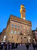 The Arnolfo Tower and the Palazzo Vecchio lit up at twilight in Florence, Italy.