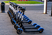 A row of rechargeable electric scooters for rent in front of the train station in La Spezia, Italy.