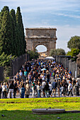 Touristen auf der Via Sacra in Richtung des Titusbogens im archäologischen Park des Kolosseums, Rom, Italien.