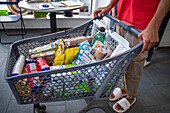 Poor and vulnerable families collecting donated products in the supermarket Rebost Solidari de Gracia, Gracia neighborhood, Barcelona, Spain, Europe. The Rebost Solidari de Gracia is a distributor entity of the Food Bank in its Sec, SERMA (fresh fruit and vegetables), cold chain (frozen and refrigerated products) and FEGA (products received from the EU) programs. An efficient management of all the food surpluses generated by the neighborhood (markets, supermarkets, shops, companies, restaurants, school canteens and others) is an important enough objective in itself, both for its use in the nei