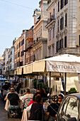 People eating in an outdoor restaurant on a street in Rome, Italy.