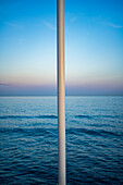 A tranquil seascape with clear sky, featuring a lamppost in Nerja, Spain.