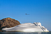 Skjoldungen Fjord. Large iceberg in scenic fjord surrounded by snow-capped mountains, Southeast coast, Greenland