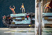 A tourist taking a polar plunge in the freezing waters of Southern Greenland, Europe. Silversea luxury cruise.