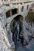 A stone archway built over the small waterfall of a stream into the harbor of Manarola, Cinque Terre, Italy.