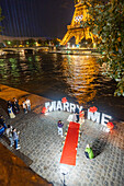 Marriage proposal and Eiffel Tower with Olympic rings at night, Paris, France