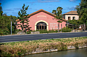 Vinauberge Bar à vin, Gîtes, Poilhes. Canal du Midi at Poilhes Aude South of France southern waterway waterways holidaymakers queue for a boat trip on the river, France, Europe