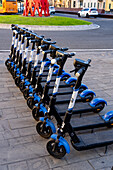 A row of rechargeable electric scooters for rent in front of the train station in La Spezia, Italy.