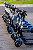 A row of rechargeable electric scooters for rent in front of the train station in La Spezia, Italy.