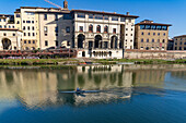 A rower in a scull on the river Arno passes the Uffizi Gallery in Florence, Italy.