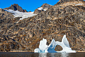 Skjoldungen Fjord. Large iceberg in scenic fjord surrounded by snow-capped mountains, Southeast coast, Greenland