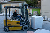 A worker at a marble carving studio moves a block of marble with a forklift. Fantiscritti, Carrara, Italy.