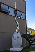 A modern art sculpture decorates the outside of a marble carving studio in Carrara, Italy. The sculpture depicts a small fairy standing on top of a cluster of grapes. Artist unknown.