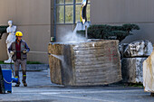 A worker powerwashes a large block of marble at a marble supply company yard in Carrara, Italy.