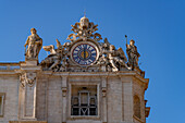 A clock and statues on the facade of Saint Peter's Basilica in Vatican City in Rome, Italy.